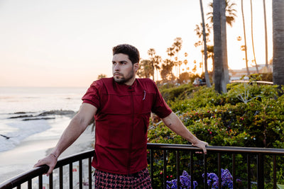 Man on a balcony, near a beach and sea, wearing a Floatee anti-drowning T-shirt red with short sleeves